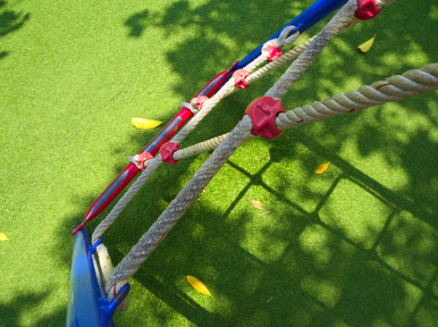 close-up view of climbing ropes on a playground with artificial grass and fallen leaves vibrant outdoor play area for children