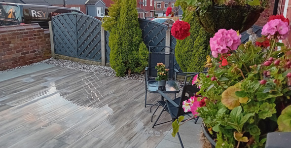 outdoor patio with chairs and flower planters featuring vibrant flowers and greenery featuring two potted plants and a shiny tile surface